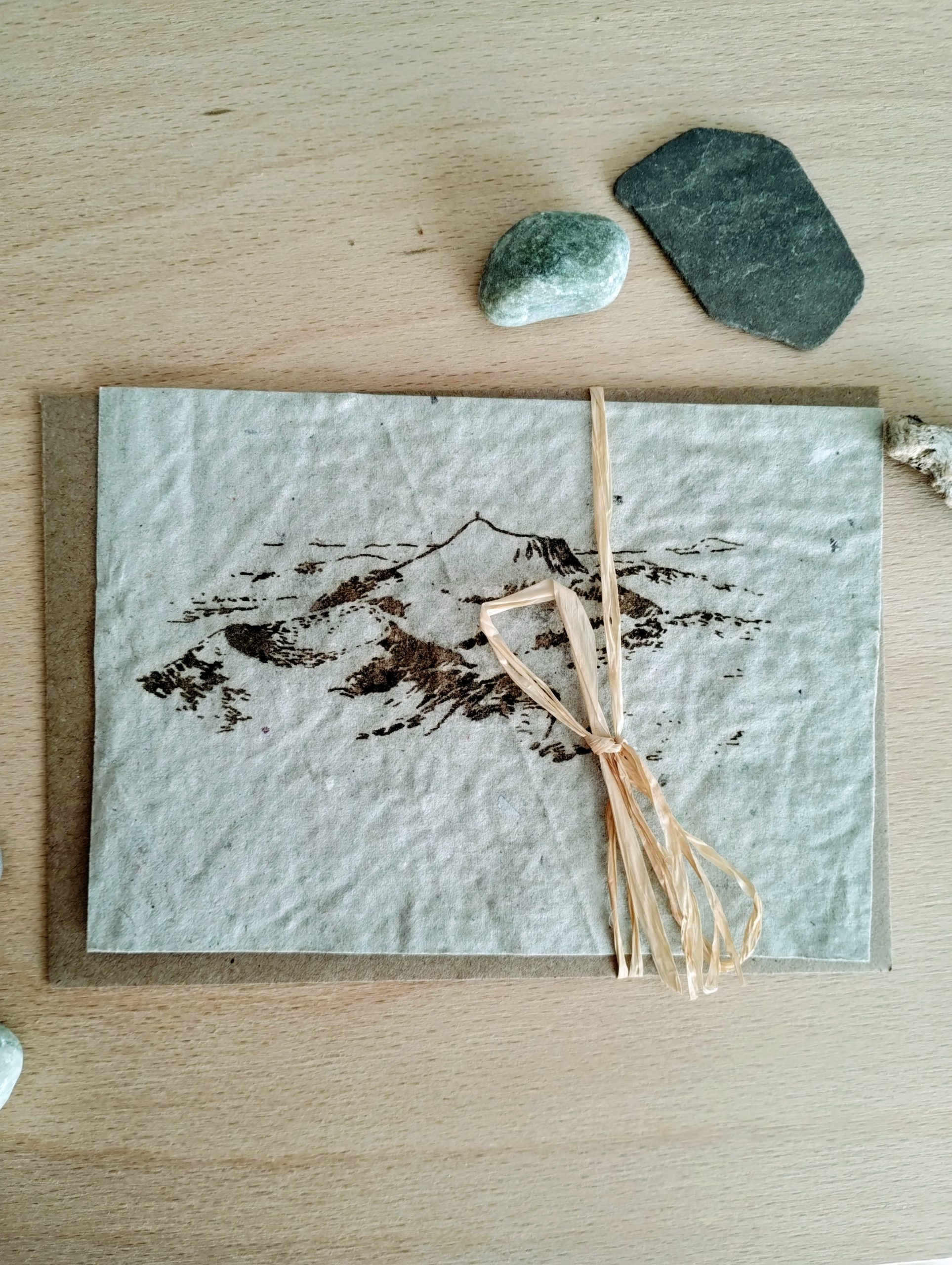 la chaine des puys représentée sur un papier recyclé aux teintes vertes pâles.