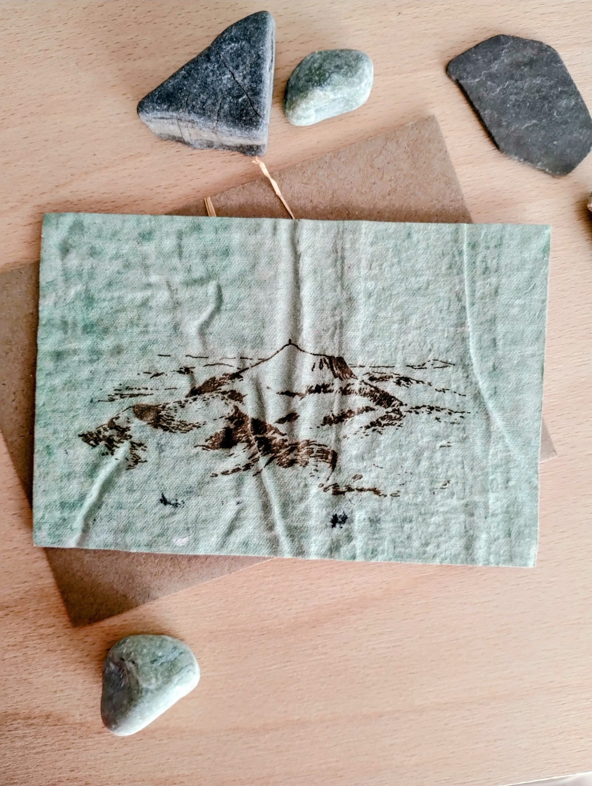 Carte postale verte avec dessin de la chaine des puys en Auvergne.