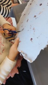 enfant en train de découper du papier recyclé pour faire sa fleur