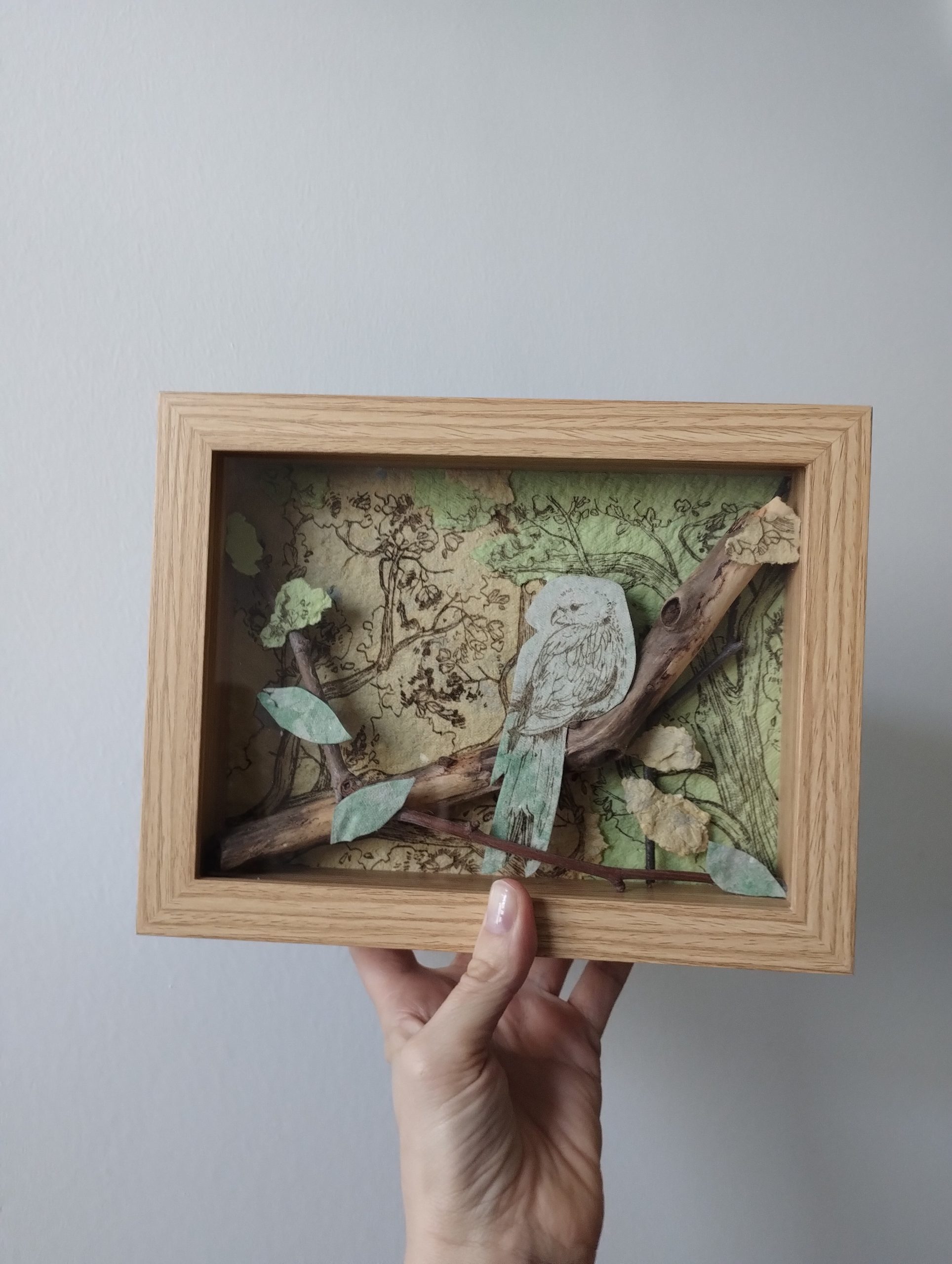 Tableau d'une perruche sur une branche. Réalisation en papier recyclé.